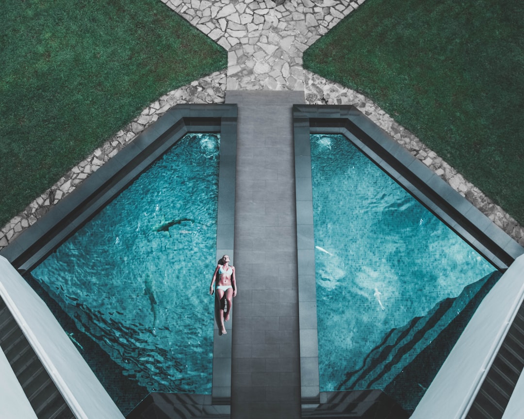 birds-eye-view-of-woman-lying-on-floor-beside-swimming-pool-r83vnlcsfo8